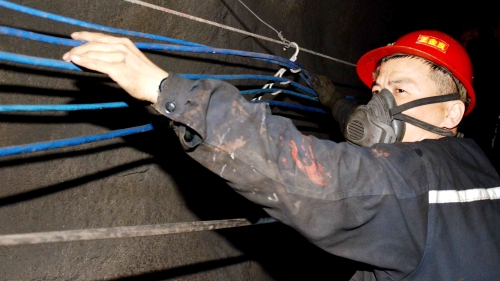 图为新兴矿提运区维修段职工王金良正在整理巷道光缆，确保清静生产。_副本