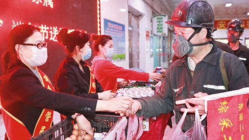 图为：东荣二矿女工将鸡蛋和牛奶递到职工手中，嘱咐“清静第一”。